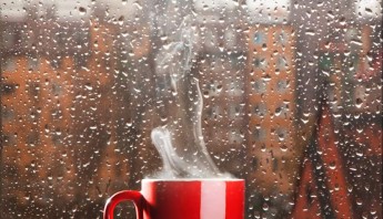 taza de cafe caliente delante de una ventana de lluvia
